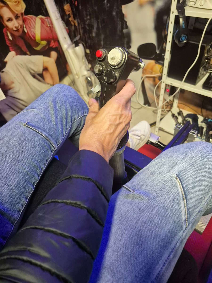 Main du pilote sur le manche cyclique du simulateur d’hélicoptère, vue depuis le siège