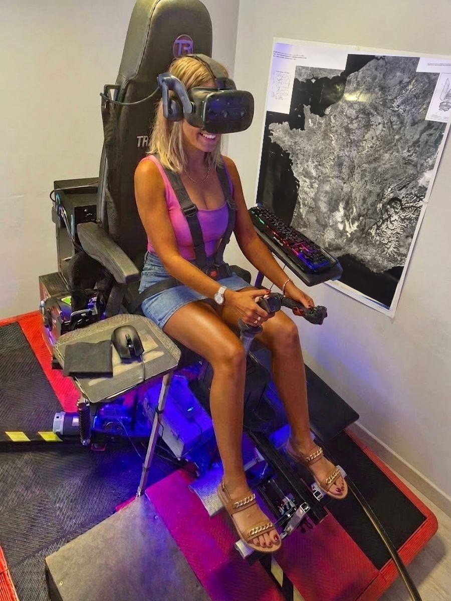 Une pilote aux commandes du simulateur d’hélicoptère à Versonnex, casque de réalité virtuelle et harnais, devant la carte de France vue de satellite